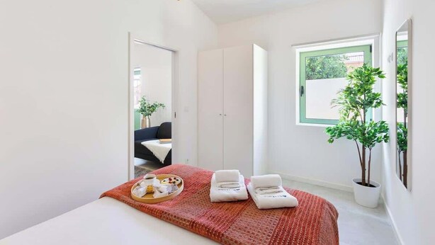 Une chambre d’hôtel moderne avec un lit, un plateau de petit-déjeuner, une plante en pot et une vue sur l’extérieur.