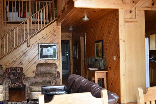 A wooden interior with a staircase, a sofa, a patterned armchair, and a small table with a plant. - 4 bedrooms and loft sleeps 12 with view  pool table 2 levels of decks and hot tub (Sevierville)