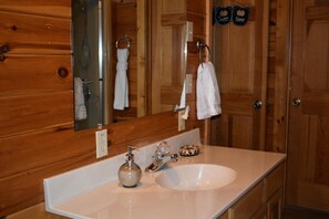 A wooden cabin bathroom with a white sink, a mirror, and two towels hanging on the wall. - 4 bedrooms and loft sleeps 12 with view  pool table 2 levels of decks and hot tub (Sevierville)