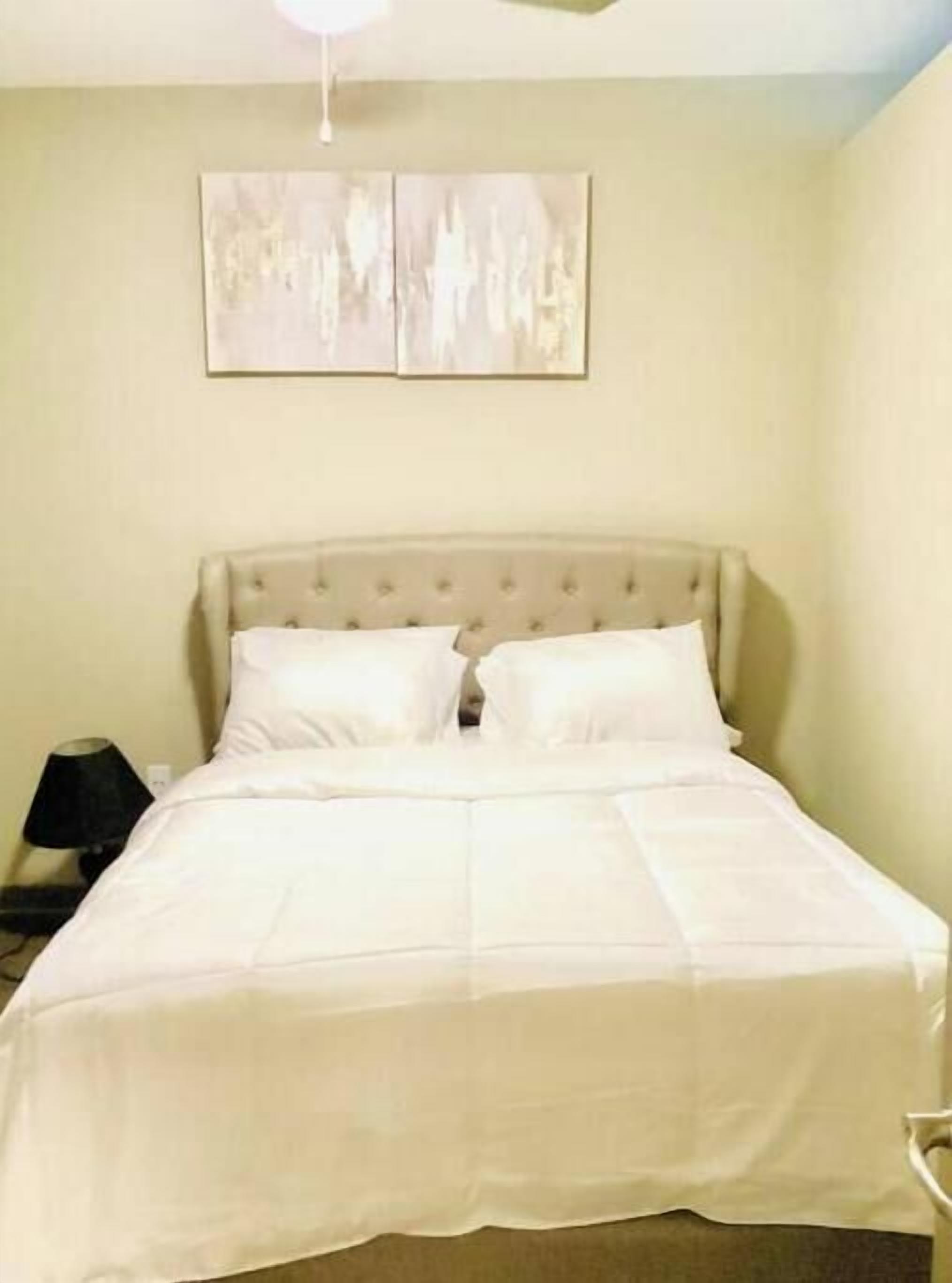 Une chambre à coucher comprenant un lit, une table de chevet et une œuvre d’art accrochée au mur.