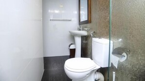 Een moderne badkamer met toilet, wastafel en een douchecabine met glazen wanden.