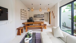 A modern living room with a sofa, a coffee table, and a dining area with a wooden bench and table. - Peaceful villa with AC in beautiful Bali (Bali)