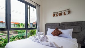 A hotel room with a large bed, a grey headboard, and a view of the outside. - Peaceful villa with AC in beautiful Bali (Bali)