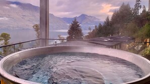Uma banheira de hidromassagem com vista para montanhas e um lago.