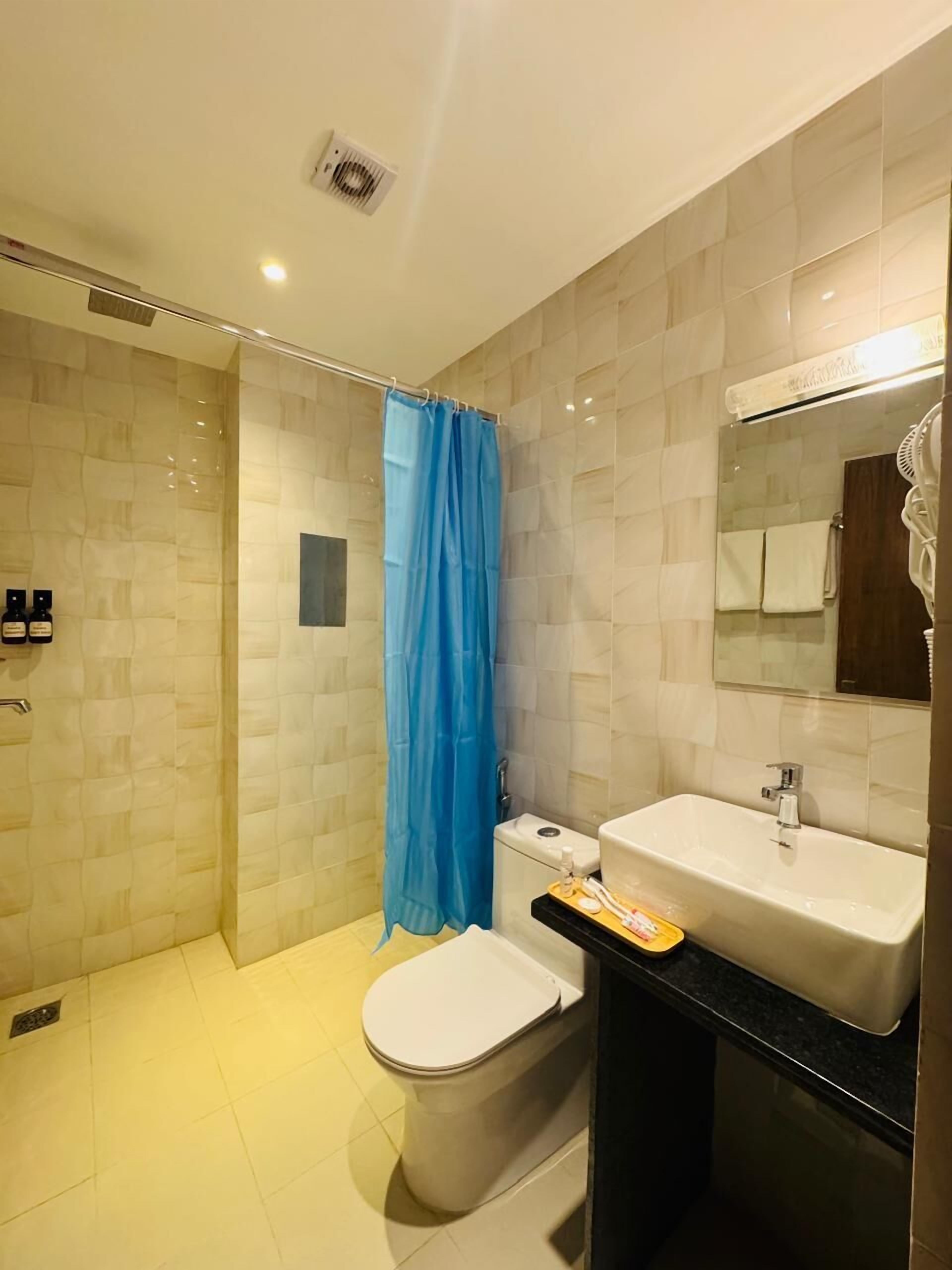 Un baño moderno con cabina de ducha de vidrio, inodoro, lavabo y espejo.