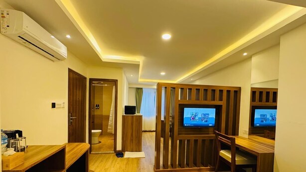 Una habitación de hotel con una cama, un escritorio con una silla, un televisor y un separador de madera.
