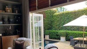 A modern living room with a large window, a pool, and outdoor furniture.