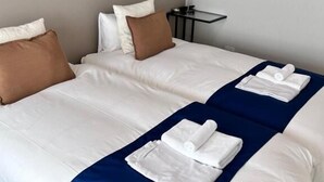 Un lit double avec une literie blanche et bleue, deux oreillers et une serviette pliée posée sur le lit.
