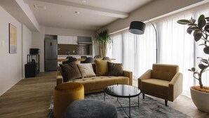 Un salon moderne avec un canapé, un fauteuil, une table basse et une plante en pot.