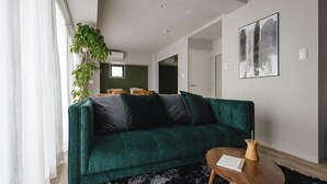 Un salon moderne avec un canapé vert, une petite table en bois et un grand tableau abstrait accroché au mur.