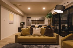 Un salon moderne avec un canapé, un coin repas et une cuisine en arrière-plan.