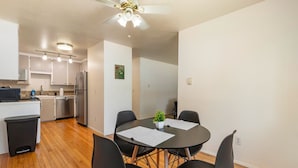 A modern kitchen with stainless steel appliances, a dining area with a round table and four chairs, and a ceiling fan. - Spacious 2BR Duplex Family Group Friendly (Lynnwood)