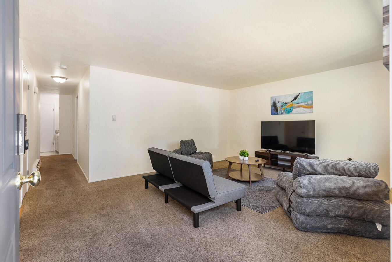 A living room with a sofa, armchair, and a TV on a stand.
