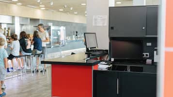 A reception area with a sign indicating 'RECEPCIÓN', a counter with a computer, and a group of people in the background.