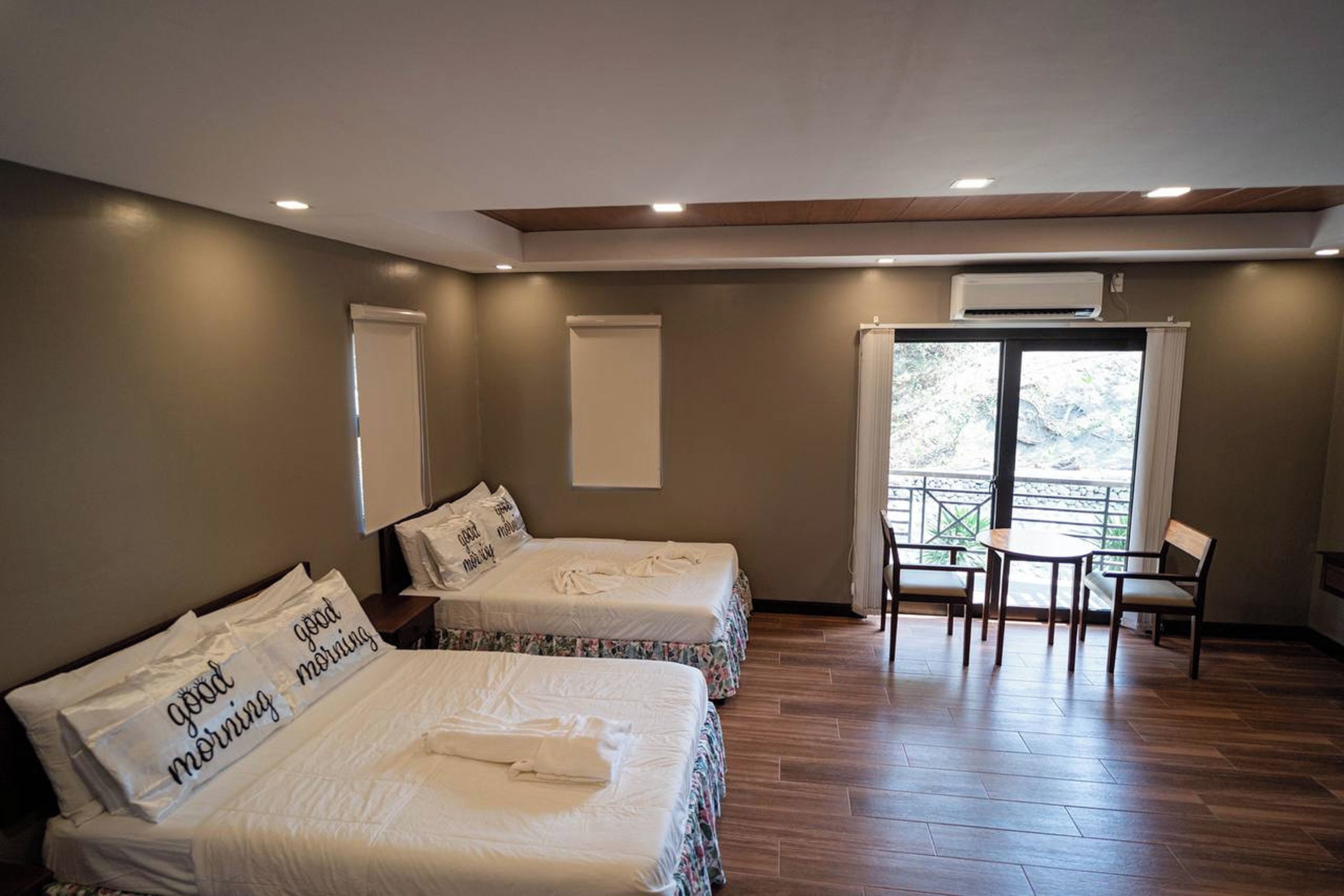 Una habitación de hotel con dos camas, un balcón y una pequeña mesa con sillas.