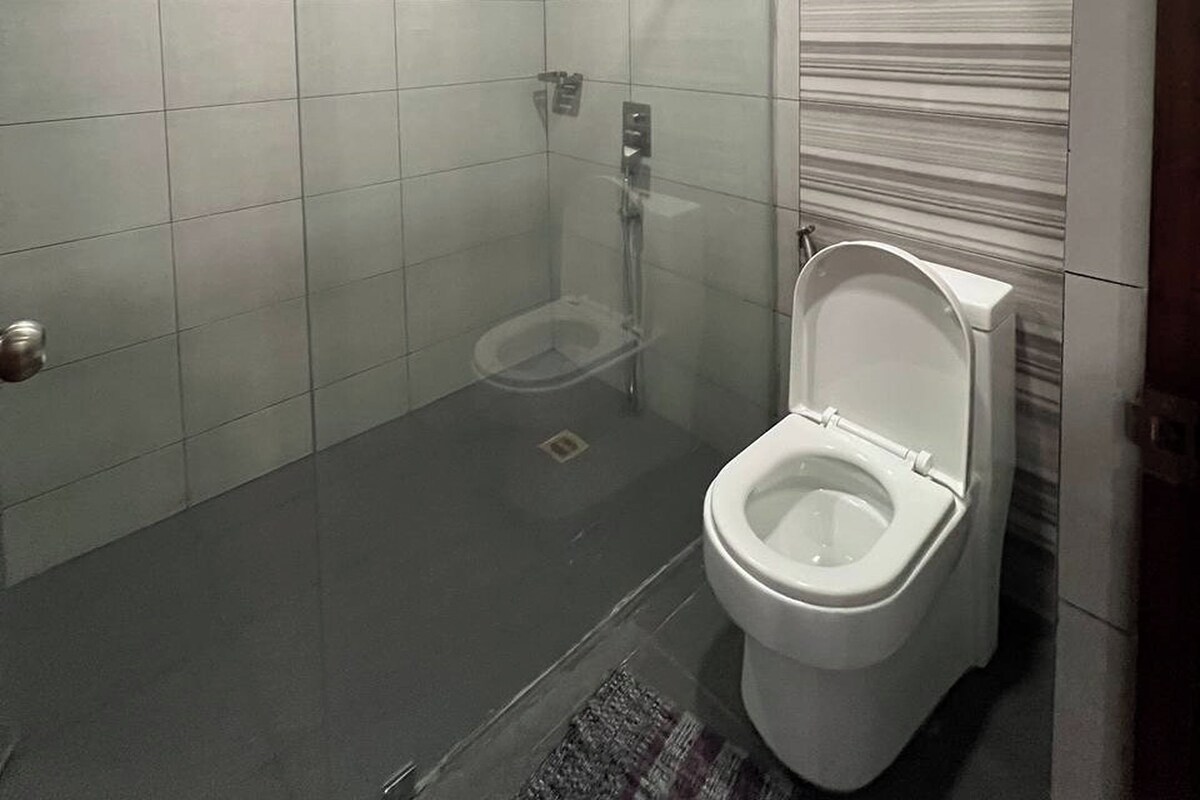 Ein Badezimmer mit Toilette, Dusche und Fliesenboden.