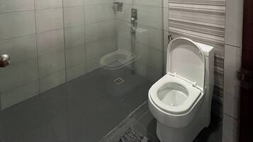 A bathroom with a toilet, a shower, and a tiled floor.