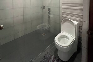 Ein Badezimmer mit Toilette, Dusche und Fliesenboden.