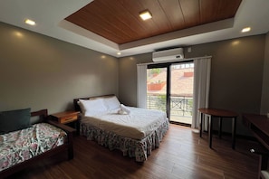 Een slaapkamer met een bed, een bijzetbed, een bureau en een raam met gordijnen.