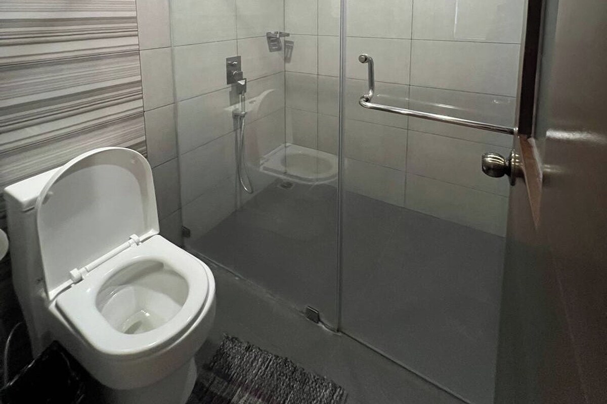 A bathroom with a toilet, a shower, and a glass-enclosed shower stall.