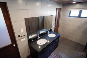 A bathroom with two sinks, a large mirror, and a wooden door. - Villa Minerva Eco-farm Resort Near Vigan By Zuzu (Caoayan)