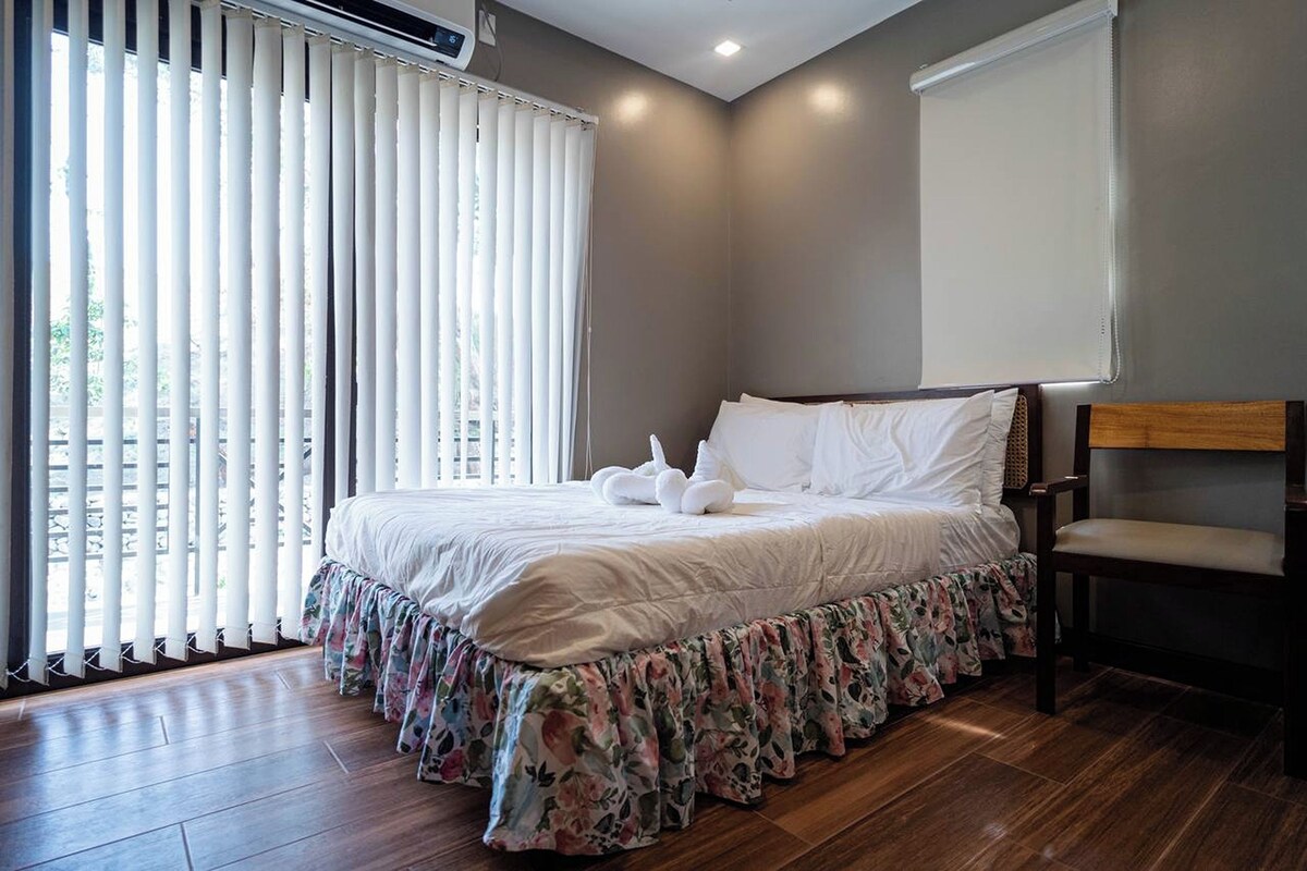 A neatly made bed with white bedding, a floral skirt, and a wooden headboard.