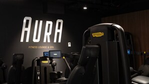 Un salón de ejercicios con un cartel en la pared que dice "AURA FITNESS LOUNGE & SPA".