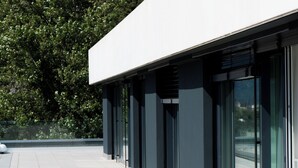 A modern building with a flat roof, large glass windows, and a tiled floor. - Arbed Living Hotel Self Check-in (Arbedo-Castione)