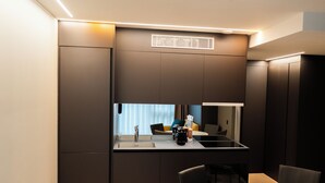 Una cocina moderna con estufa integrada, un lavamanos y una zona de comedor con una mesa redonda y sillas.