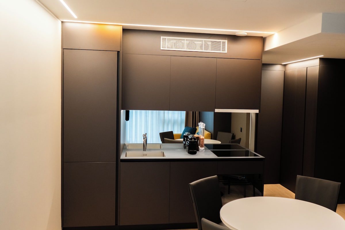 A modern kitchen with a built-in stove, a sink, and a dining area with a round table and chairs.