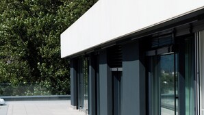 Un edificio moderno con techo plano, grandes ventanales y piso de baldosas.