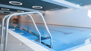 A swimming pool with a metal ladder, tiled floor, and a ceiling with circular lights. - Arbed Living Hotel Self Check-in (Arbedo-Castione)