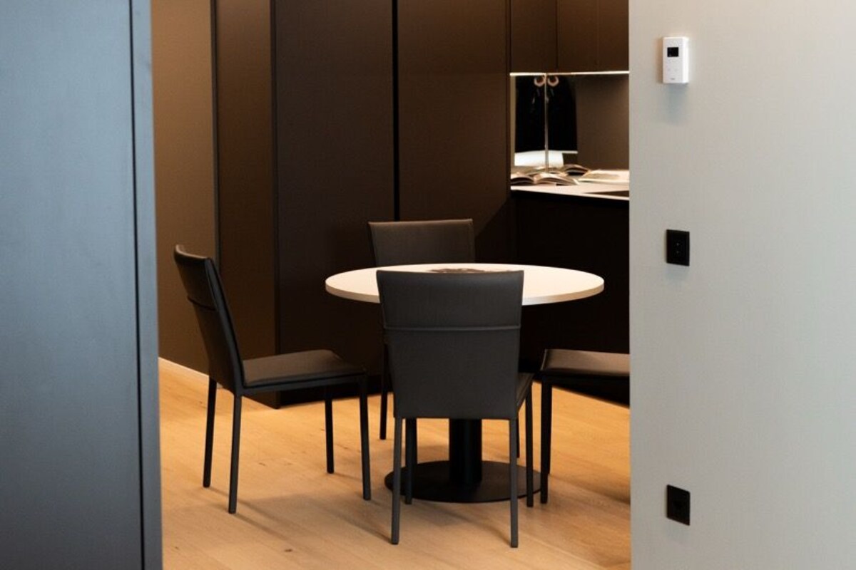 A modern room with a round table, four chairs, and a light fixture above.