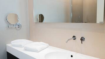 Une salle de bain moderne avec un lavabo blanc, deux miroirs et un miroir à main.