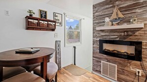 Una habitación acogedora con una mesa redonda de madera, una chimenea y una ventana con vistas.