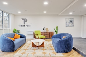 A modern living room with two blue sofas, a coffee table, and a wall-mounted air conditioning unit.