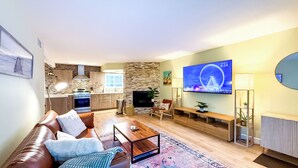 Un salon moderne avec un canapé en cuir marron, une table basse et un téléviseur diffusant une image d’une grande roue.