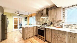 Une cuisine moderne avec des meubles en bois, une cuisinière en acier inoxydable et une grande fenêtre.