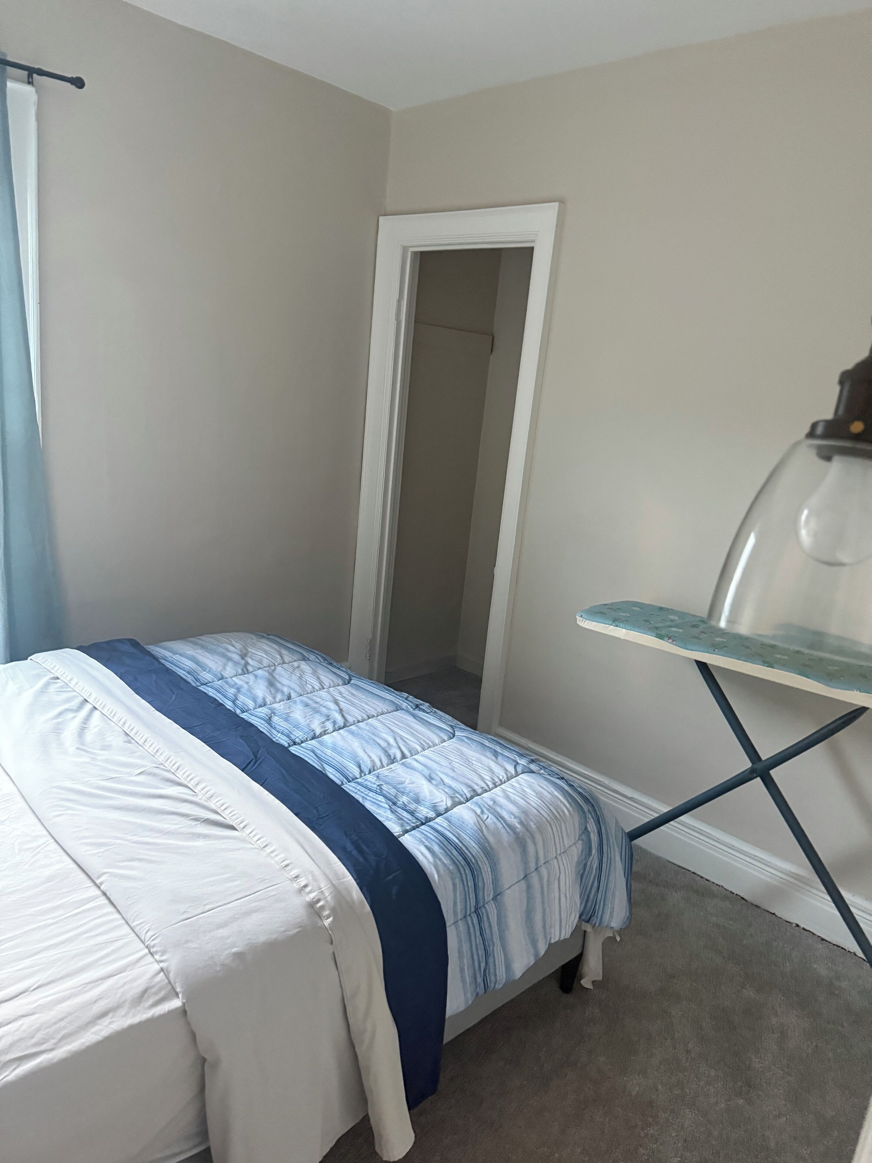 Een slaapkamer met een bed, een stoel en een deur naar een andere kamer.