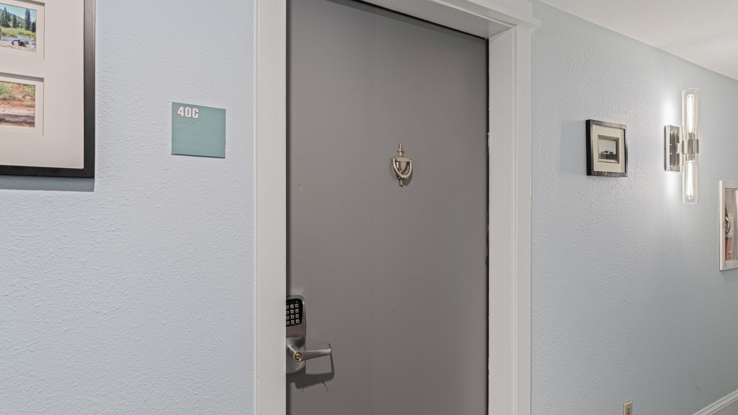 A door with a keypad lock, a small sign reading '40C', and framed pictures on the wall.