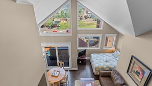 Un dormitorio con una ventana grande, una cama, un escritorio y vistas al exterior.