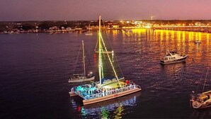Un grand bateau, illuminé de nombreuses lumières, était amarré dans un port, avec une vue sur la ville en arrière-plan.