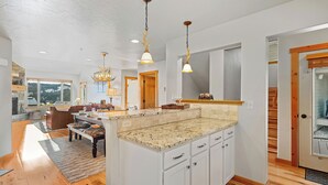 A spacious kitchen with a large island, wooden cabinets, and pendant lighting. - Walk to Town Center Shops & Restaurants, Private Hot Tub, 3BR + Loft (Big Sky)