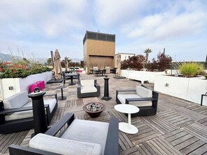 Eine Dachterrasse mit Sitzgelegenheiten im Freien, einem Grillbereich und Blick auf die Stadtlandschaft.