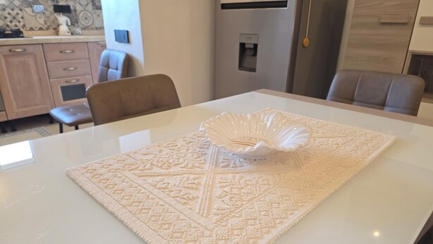Une table à manger recouverte d’une nappe blanche et agrémentée d’un vase décoratif.