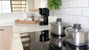 A modern kitchen with a built-in induction cooktop, stainless steel pots, a coffee maker, and a potted plant. - Penthouse with private jacuzzi, beach access, perfect for long stays! (Punta Cana)