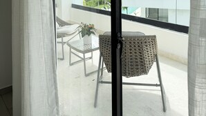 A balcony with wicker furniture and a hanging light fixture. - Penthouse with private jacuzzi, beach access, perfect for long stays! (Punta Cana)