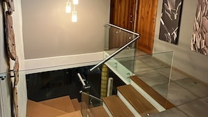Un interior moderno con una escalera de cristal, tragaluces y obras de arte contemporáneas.