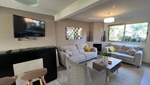 Una sala de estar moderna con dos sofás, una mesa de centro, un televisor y una chimenea.
