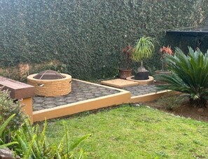 A garden with a stone pathway, potted plants, and a wooden bench.